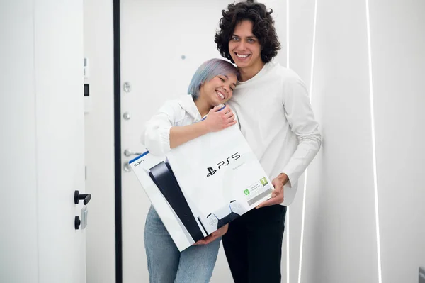 Happy young couple just came home from store with a brand new Sony PlayStation 5 gaming console. They got it on a Black Friday sale. Moscow - November 28 2020. — Stock Photo, Image