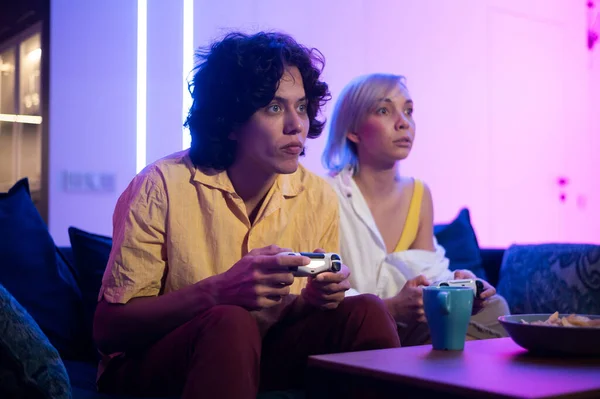 Couple jouant au jeu vidéo sur console. Fille perdre et ne pas laisser le gars jouer normalement en fermant les yeux avec sa main. S'amuser ensemble à la maison en quarantaine. — Photo