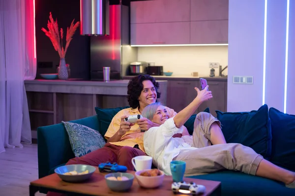 Happy young couple playing and winning a game funny activity sitting home on a sofa — Stock Photo, Image