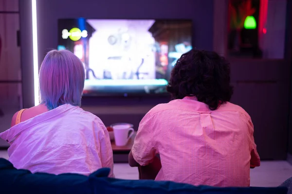 Hermosa chica de pelo azul y chico joven sosteniendo contorllers de juegos jugando videojuegos en casa. — Foto de Stock