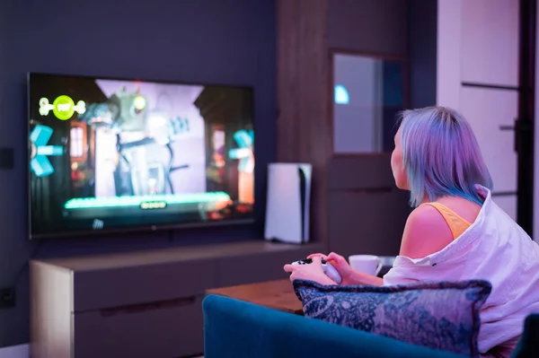 Schöne blauhaarige Mädchen mit Gaming-Verrenker, die Videospiele zu Hause spielen. Rückseite. — Stockfoto