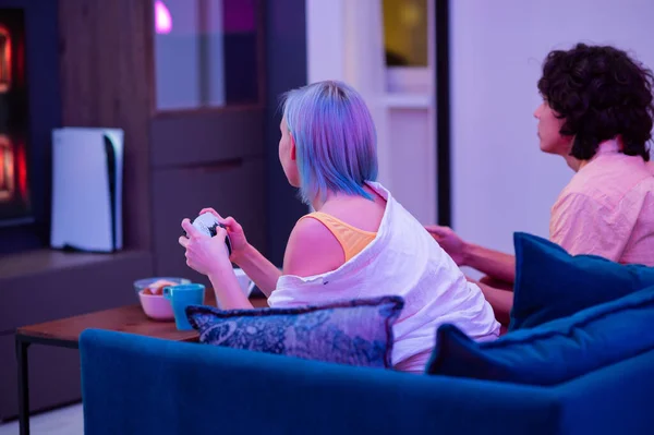 Young adult couple boy and girl playing video game console, having fun, back view. — Stock Photo, Image