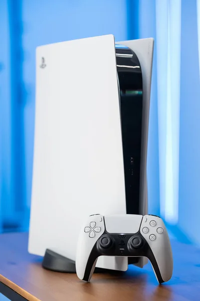 Die neue Sony Spielekonsole PlayStation 5 und der DualSense-Controller in blauem Neonlicht. Moskau - 28. November 2020. — Stockfoto