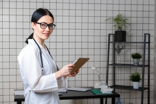 Médico con máscara médica en el escritorio en la oficina mirando la cámara — Foto de Stock