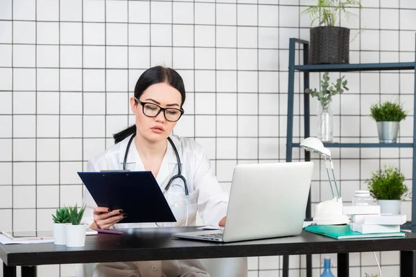 Mujer asistente de laboratorio trabajando en su escritorio, hospital, documentos — Foto de Stock