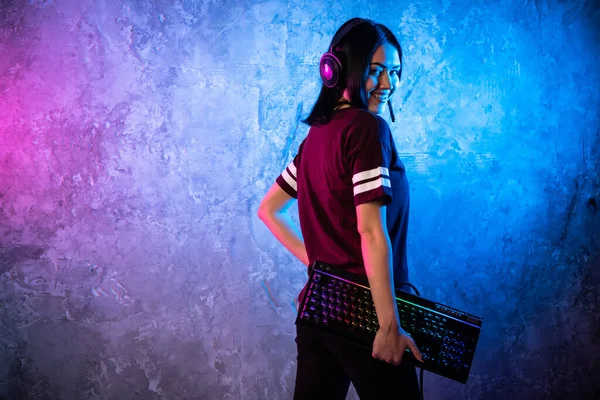 Female esports gamer posing with a gaming gear in neon light. Streamer girl standing with a gaming keyboard. — Stock Photo, Image
