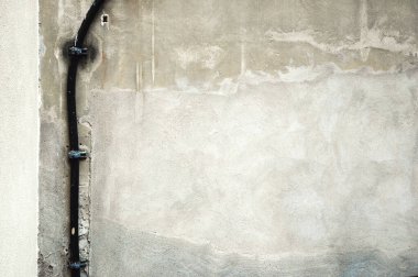 Etkileyici kablosu olan eski gri ev duvarı açıkça görülüyor ki çoğu zaman tamir edilmiş bir yapı.