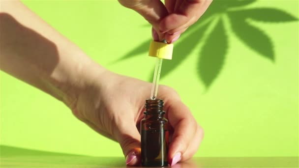 女用滴水器 加大麻头皮麻油滴在绿色背景玻璃瓶中 — 图库视频影像