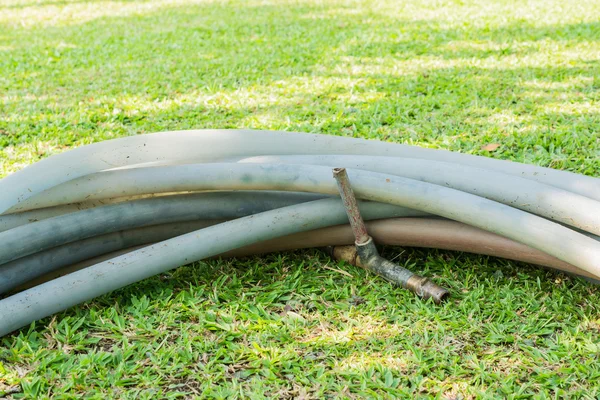 Tubo di gomma con rubinetto sul campo di erba verde — Foto Stock