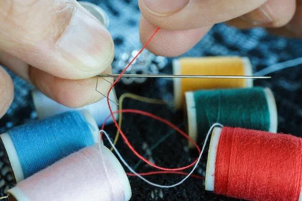 Closeup hand pulling thread into needle — Stock Photo, Image
