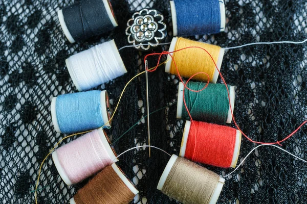 Colorful thread and needle on black fabric — Stock Photo, Image