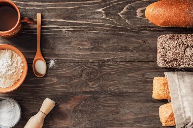 Ekmek pişirmek için gereken malzemeler ve ahşap arka planda bulunan çeşitli taze ekmekler. Sağlıklı, lezzetli organik yiyecekler.