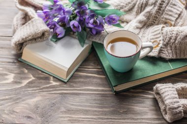 Bahar sabahı kahvesi. Tahta bir masada bir fincan kahve ve bir buket bahar çiçeğinin arka planında sıcak bir kazak. Hayat konsepti. Sıcak bir sabah. 