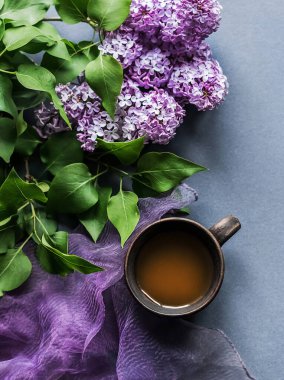 Bir fincan sabah kahvesi ve leylak arkaplanda bir dal leylak. Yukarıdan bak. Yakın plan tatil ve günaydın dilekleri..