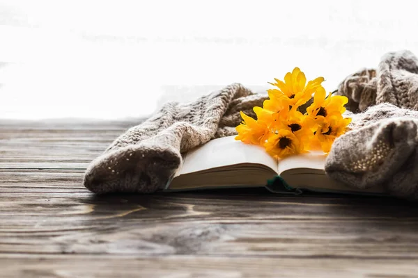 Cozy morning. Opened book and a bouquet of flowers on a wooden background with copy space. Cozy home interior, lifestyle, romantic atmosphere.