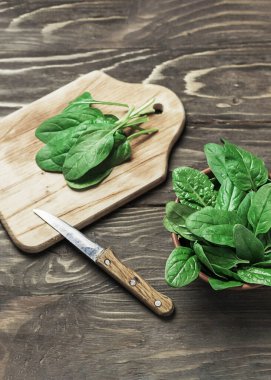 Kırsal ahşap bir masada, kasede taze ıspanak yaprakları. Seçici odak.