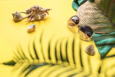 Plaj aksesuarları ve palmiye ağaçları ile aydınlık yaz geçmişi. Hasır şapka, güneş gözlüğü ve deniz kabuğu. Kopyalama alanı olan düz.