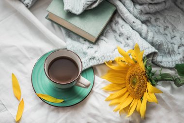 Sabah kahvesi. Konforlu kompozisyon: Ahşap bir masada bir fincan kahve ve kitapta sıcak bir süveter. Hayat konsepti. Boşluğu kopyala.