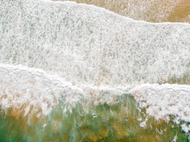 Aerial view of the sea with an emerald green color and large foaming waves