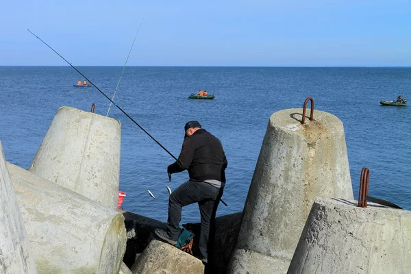 Pesca marítima - o pescador remove a espadilha capturada — Fotografia de Stock