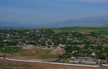                     Houses on the top of the hill, mountain in the background           
