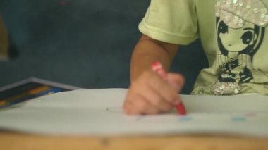 Bir kız odasında oturur ve resim çizer..