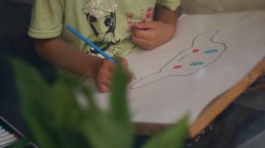 Bir kız odasında oturur ve resim çizer..