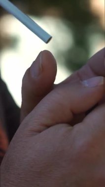 Bir adam sigarasını yavaşça yakıyor.