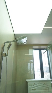Minimalist iç tasarım: Cam bölmeli ve parlak ışıklandırmalı modern banyo.
