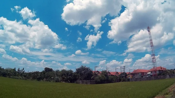 Sininen taivas, vihreät pellot ja pieni kylä — kuvapankkivalokuva