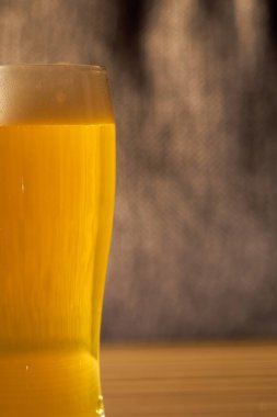 Arka planda bulanık bir bardakta hafif köpüklü bira. Boşluğu kopyala.