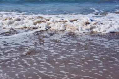 Akdeniz 'in kumlu sahilinde köpüklü dalgalar ufkun ötesine gidiyor. Boşluğu kopyala.