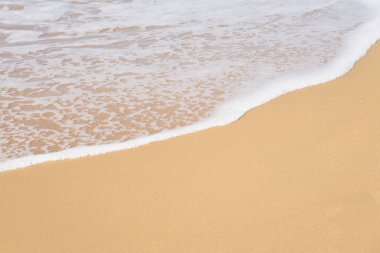 Akdeniz 'in kumlu sahilinde köpüklü dalgalar ufkun ötesine gidiyor. Boşluğu kopyala.