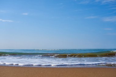 Akdeniz 'in kumlu sahilinde köpüklü dalgalar ufkun ötesine gidiyor. Doğal arkaplan.