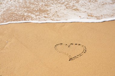 Kalbim kumsalda kumlara ve dalgaların köpüğüne boyanmış. Sevgililer Günü konsepti.