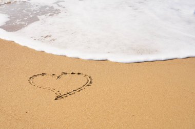 Kalbim kumsalda kumlara ve dalgaların köpüğüne boyanmış. Sevgililer Günü konsepti.