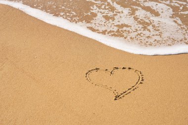 Kalbim kumsalda kumlara ve dalgaların köpüğüne boyanmış. Sevgililer Günü konsepti.