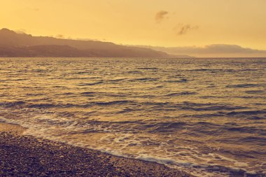 Gün batımında Girit 'teki Kolymbari' de çakıl taşı plajı. Boşluğu kopyala.