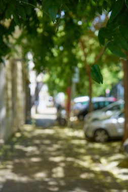 Ağaçları ve arabaları olan bulanık bir cadde şehir arka planı gibidir..