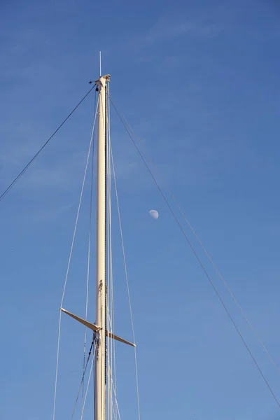 The yacht\'s mast against the blue sky with the moon with space for text.