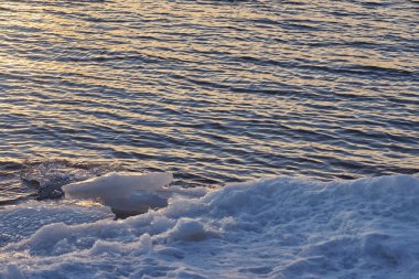 Baharda gün batımında denizin buzlu kıyıları.