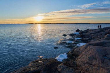 İlkbaharda Baltık Denizi 'nin taştan kıyısı. Güneş ışığındaki buz kalıntılarıyla birlikte..