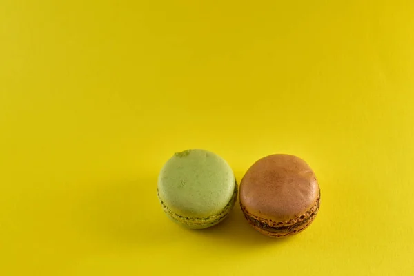 Sarı arkaplan aromalı badem kurabiyeleri üzerine pasta makaronu üst görünümü pastel renkler ve metin için boşluk.