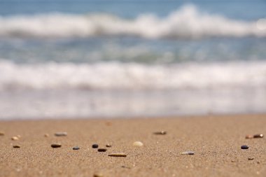 Arka planda bulanık dalgalar olan tropikal sahilde çakıl taşı