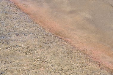 Girit 'teki tropikal kumlu sahilde berrak dalgalar ve renkli kumlar