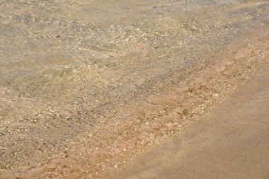 Girit 'teki tropikal kumlu sahilde berrak dalgalar ve renkli kumlar