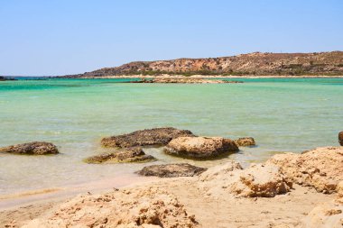 Girit Yunanistan 'da taşlı tropikal kumlu plajda berrak su yüzeyi