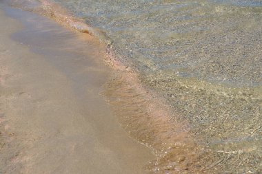 Girit 'teki tropikal kumlu sahilde berrak dalgalar ve renkli kumlar