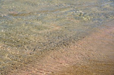 Girit 'teki tropikal kumlu sahilde berrak dalgalar ve renkli kumlar