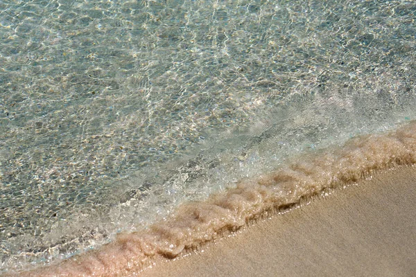 Καθαρά κύματα και πολύχρωμη άμμος σε τροπική αμμώδη παραλία στην Κρήτη. — Φωτογραφία Αρχείου